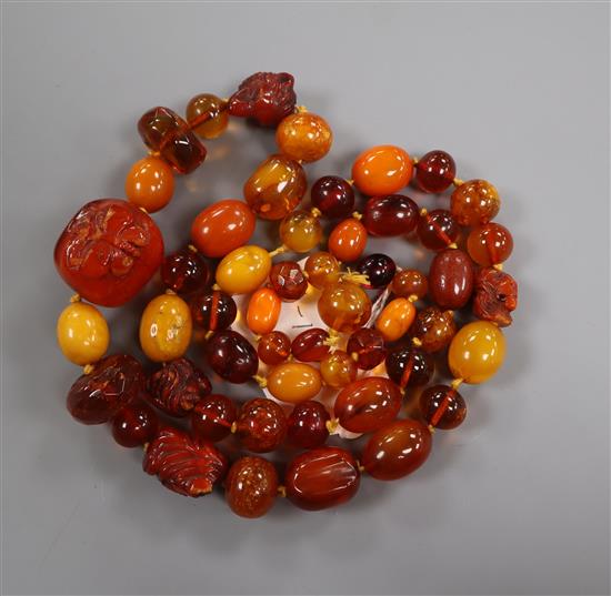 A graduated amber bead necklace, some beads carved with insects or animal heads, gross weight 119 grams, 88cm.